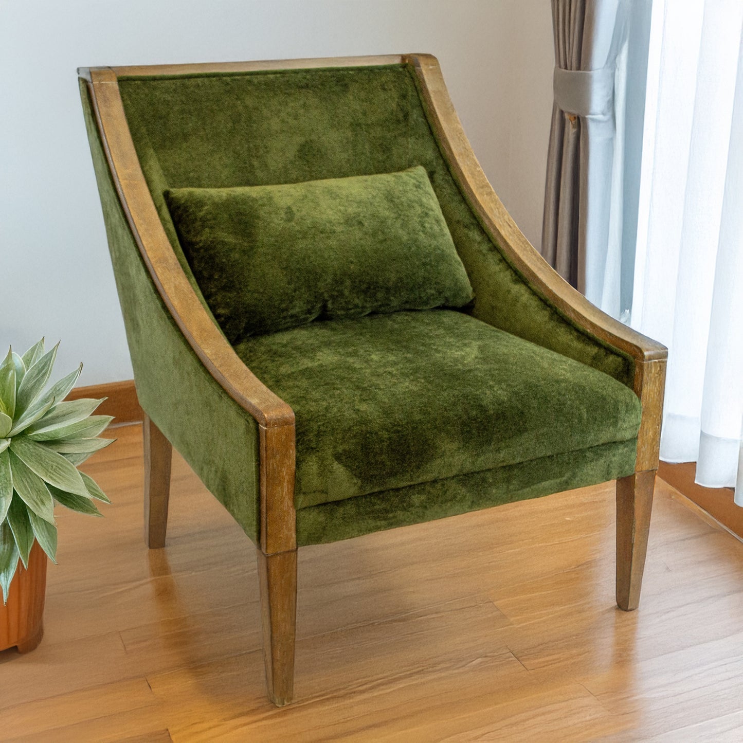 Green velvet armchair with wooden frame on a wooden floor